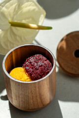 Eco-friendly wooden glass for serving ice cream in upmarket establishments. Fruit sorbet ice cream served in a wooden glass against a backdrop of shadows on a sunny day in a restaurant. Concept of