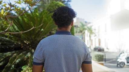 Fototapeta premium Man standing in urban park with lush plants and city buildings in background during daytime