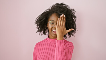 African american woman smiling indoors wearing glasses and a pink sweater