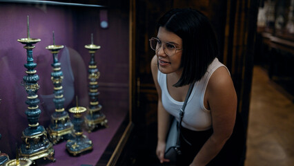 Young beautiful hispanic woman looking at art exhibition at imperial treasure museum in Vienna