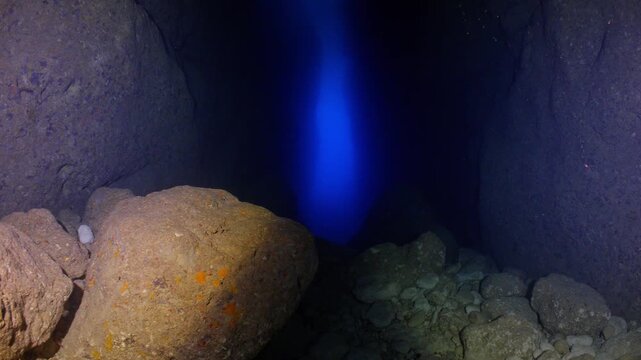 POV shot swimming through dark underwater cave with Azure Window in distance