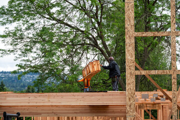 Residential house construction, boom crane lifting lumber delivery, wood support truss beams,...