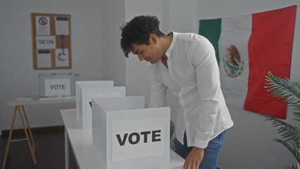 A young hispanic man votes in a room adorned with the mexican flag, symbolizing democratic...