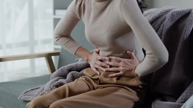 Woman has stomach ache and press hands to stomach due to menstrual cramps period cramps splenomegaly  food poisoning excess gas or acid