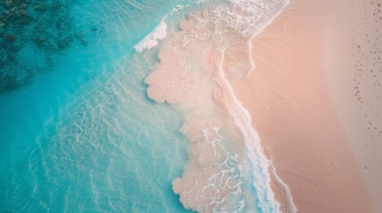 An aerial view captures the gentle embrace between the azure waves and the soft sandy beach, creating a tranquil and picturesque scene 