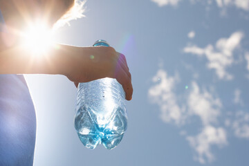 Person holding a bottle of drinking water on a hot sunny summer day 