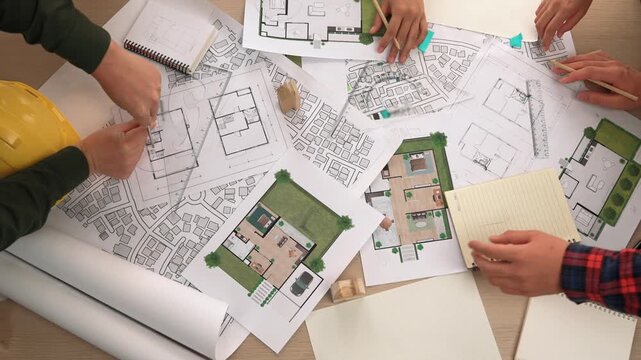 Architect and safety engineer discussion about building construction use blueprint on table with architectural document, measurement tool and wooden block scatter around at modern office. Delineation.