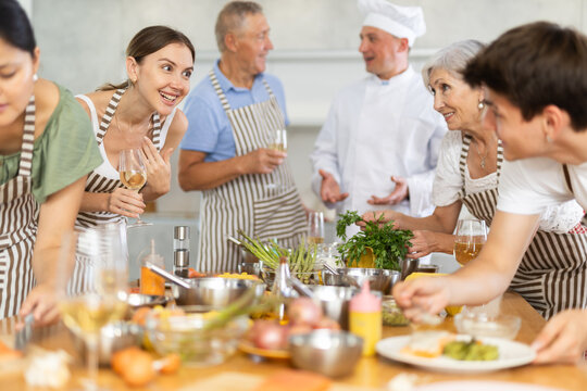 Group of different people drinking wine and talking after cooking master class