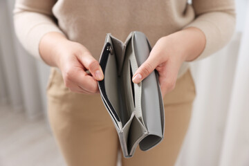 Woman with empty wallet indoors, closeup view