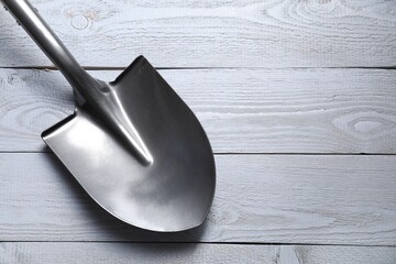 Metal shovel on light grey wooden table, top view. Space for text