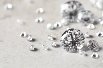 Many beautiful shiny diamonds on light background, closeup