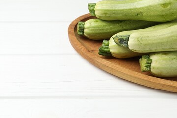 Raw green zucchinis on white wooden table, space for text