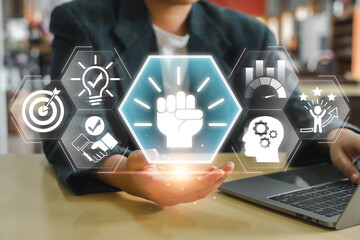 Naklejka premium Businessman holding holographic icons symbolizing motivation, success, innovation, and growth, ideal for business and professional themes.