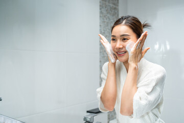 Fototapeta premium Asian beautiful woman washing her clean face with facial foam and water. 