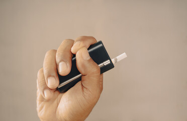Heat not burn type(HNB) Electronic cigarette heater in hand on light brown background color, it's...