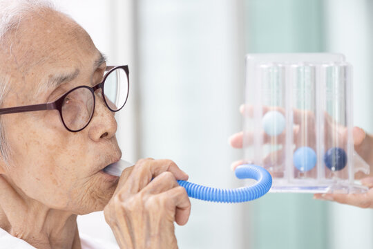 Asian senior woman using incentive spirometer,check her lung,pulmonary function test,measuring the air capacity of lungs,breathing,taking air into and expelling it from the lungs,healthcare,medical