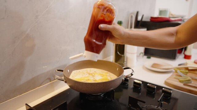 Adding Ketchup to the Pan, Enhancing the Breakfast Wrap with Extra Flavor.