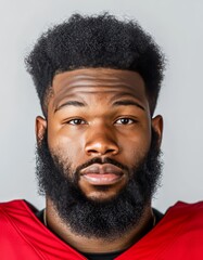 headshot of an African American football player with a black beard, wearing a red jersey, isolated on a light grey background with soft studio lighting. The portrait is in the style of a realistic