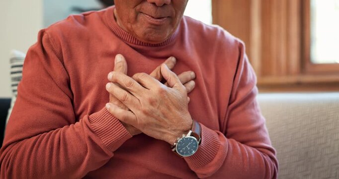 Hands, heart attack and senior man on sofa with lungs, problem or breathe, risk or emergency closeup. Chest pain, zoom and elderly person with anxiety, asthma or heartburn, stress or panic in a house