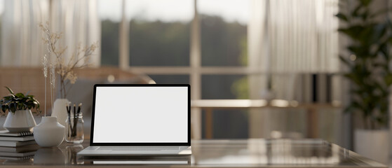 A laptop computer with a white-screen mockup and decor on a table in a cozy Scandinavian living room