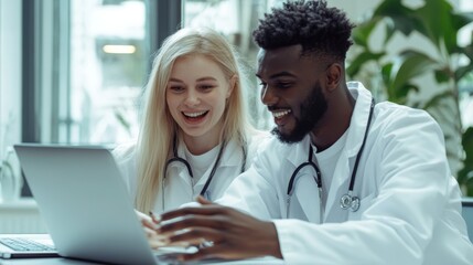 Two doctors are looking at a laptop together