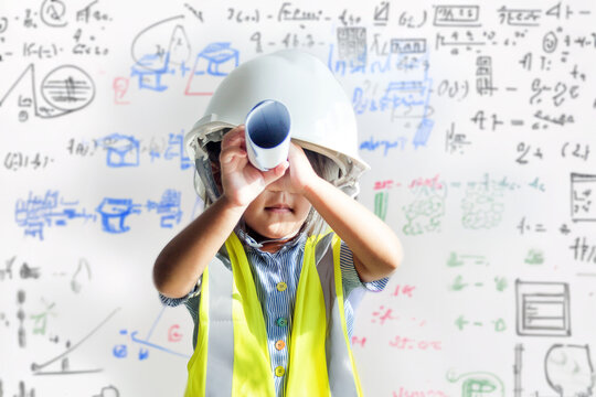 Asian kid hold role of paper as telescope with safety shirt and helmet engineer on imagine in math and bulding sketch on white board