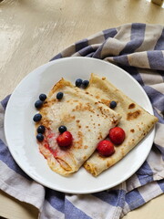 Pancakes with strawberries and blueberries on a wooden table