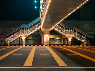 Empty asphalt road under the bridge during the night with beautiful city lights background and...