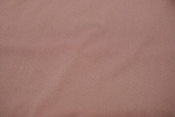 Close up photo of folded polyester fabric texture, brown rose gold color polyester fabric texture used as background. Copy space
