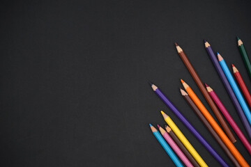 Flat lay top view of kids coloring pencils isolated on black sheet textures background banner. Back to school concept. Copy space