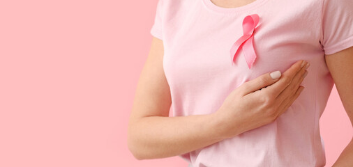 Young woman in t-shirt with pink ribbon on color background, closeup. Breast cancer awareness concept