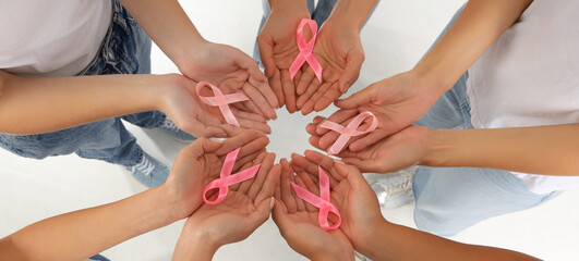 Women with awareness pink ribbons on white background, top view. Breast cancer concept