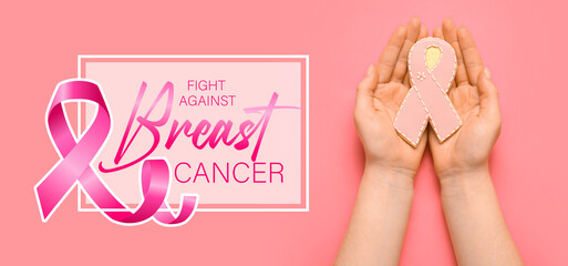 Female hands with cookie in shape of pink ribbon on color background. Breast cancer awareness...