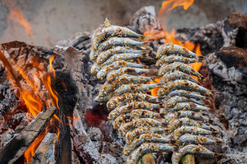 Grilled sardines, known as Espetos, are a traditional Spanish cuisine in Malaga, Spain. The fresh fish is cooked on skewers over an open wood fire barbeque pit grill shaped as a boat. Málaga sardines.