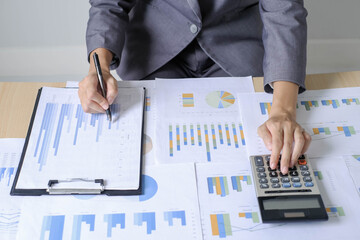 Asian businesswoman sit at their desks and calculate financial graphs showing results about their...