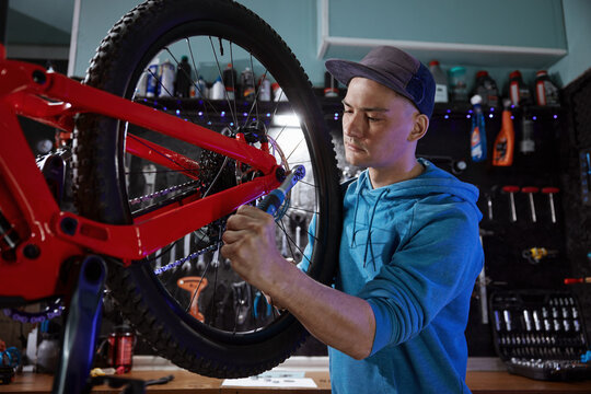 Closeup of hipster man bike mechanic removing rear wheel at garage workshop