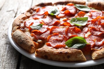 Tasty pepperoni pizza with basil on wooden table, closeup