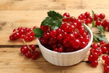 Fresh red currants and green leaves on wooden table, closeup