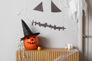 Halloween pumpkins with skeleton and candles on commode in hall