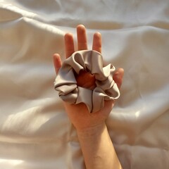 the scrunch rubber band lies on the hand of the silk