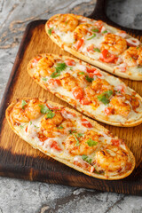 Hot baked sandwiches with shrimps, cheese, garlic and tomatoes close-up on a wooden board on the table. Vertical