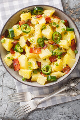 Jalapeno Popper Potato Salad with bacon, onion seasoned with mayonnaise closeup on the bowl on the table. Vertical top view from above
