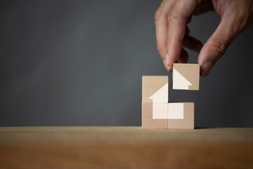Businessman's hand holds a wooden block template with a house symbol. Real estate agents provide home services. Property insurance and security Affordable housing concept
