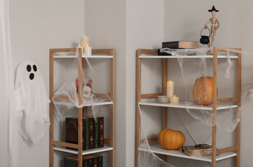 Shelf units with books, candles and Halloween decor in light room