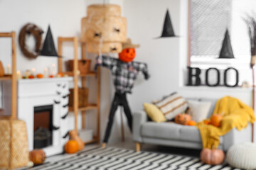 Blurred view of living room decorated for Halloween with fireplace, scarecrow and sofa