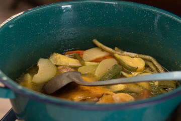 A pot of homemade vegetable soup, including green beans, zucchini and carrots, at a Mexican market food stand in a traditional market