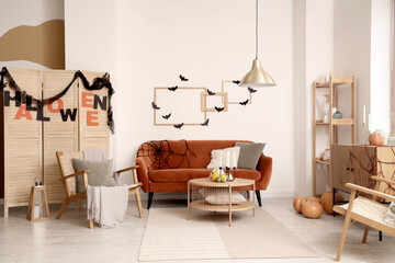 Interior of living room decorated for Halloween with red sofa and armchair