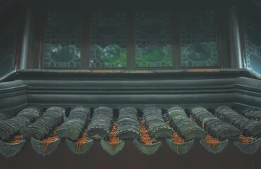 A close up of a traditional Chinese roof with intricate patterns and green moss.
