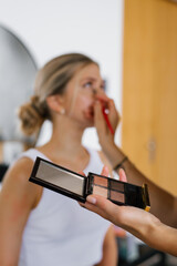 Palette for shadows in the hands of a makeup artist in close-up on the background of a model