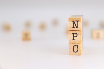 NPC acronym - Non-Player Character written in English language on wooden cubes isolated on white background with copy space for text.